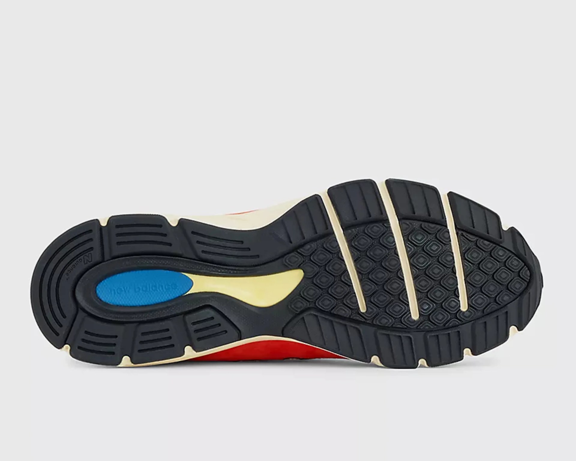 Black rubber outsole with blue, yellow, and red accents and "new balance" text in blue area.