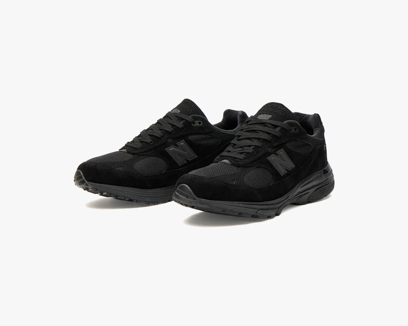 Pair of black New Balance sneakers with suede and mesh upper and black rubber soles on a white background.