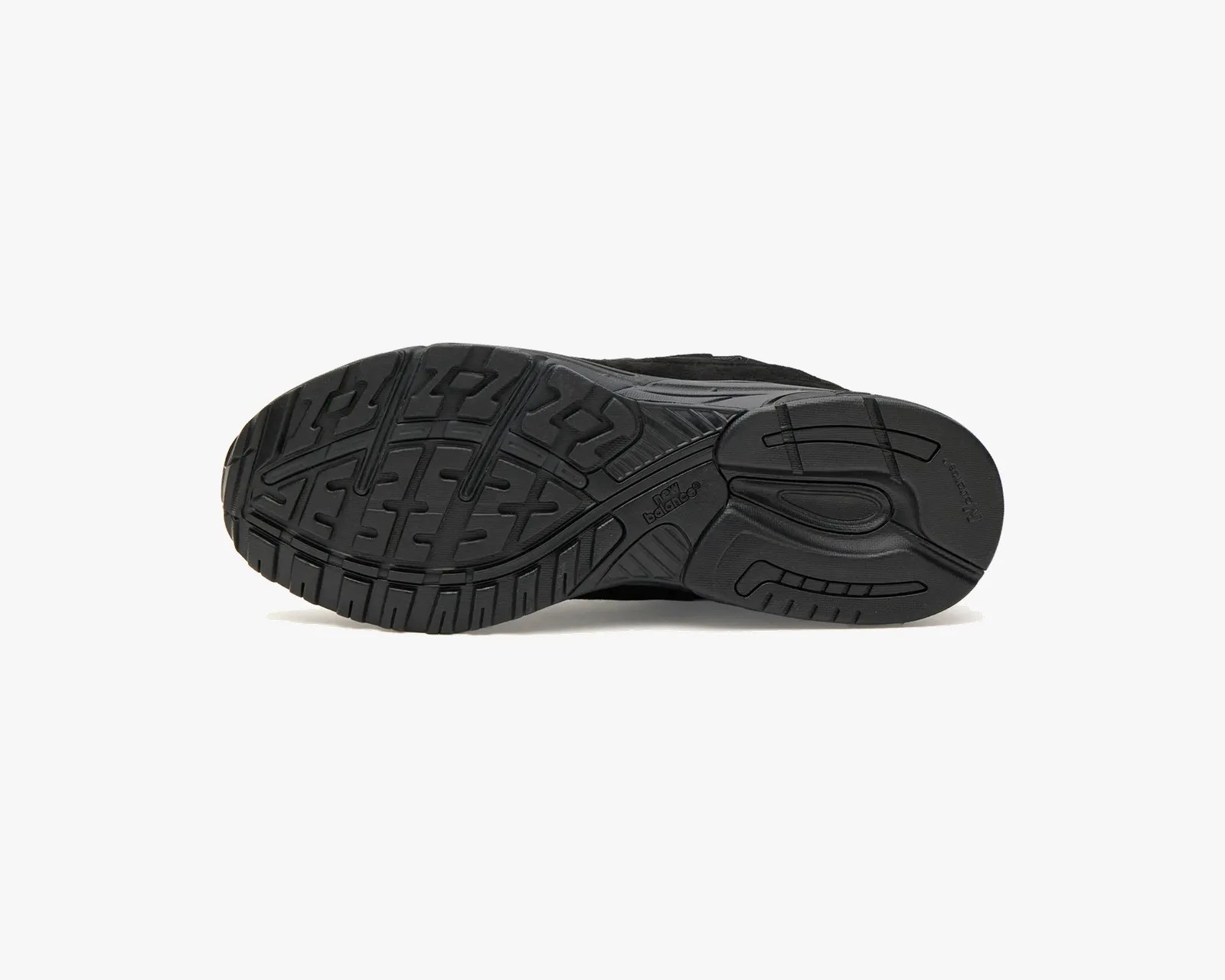 Black rubber outsole of a New Balance shoe with textured tread pattern.