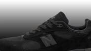 Close-up of a black New Balance sneaker with mesh and suede panels and gray "N" logo on the side.