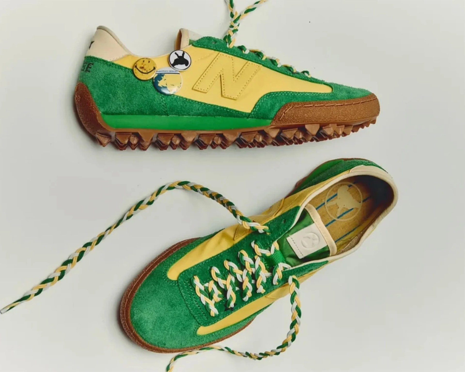 Green and yellow suede sneakers with brown textured soles and braided green, yellow, and white laces.