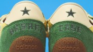 Close-up of green and cream New Balance sneakers with embroidered black stars and "BASKET CASE" text on the heels.