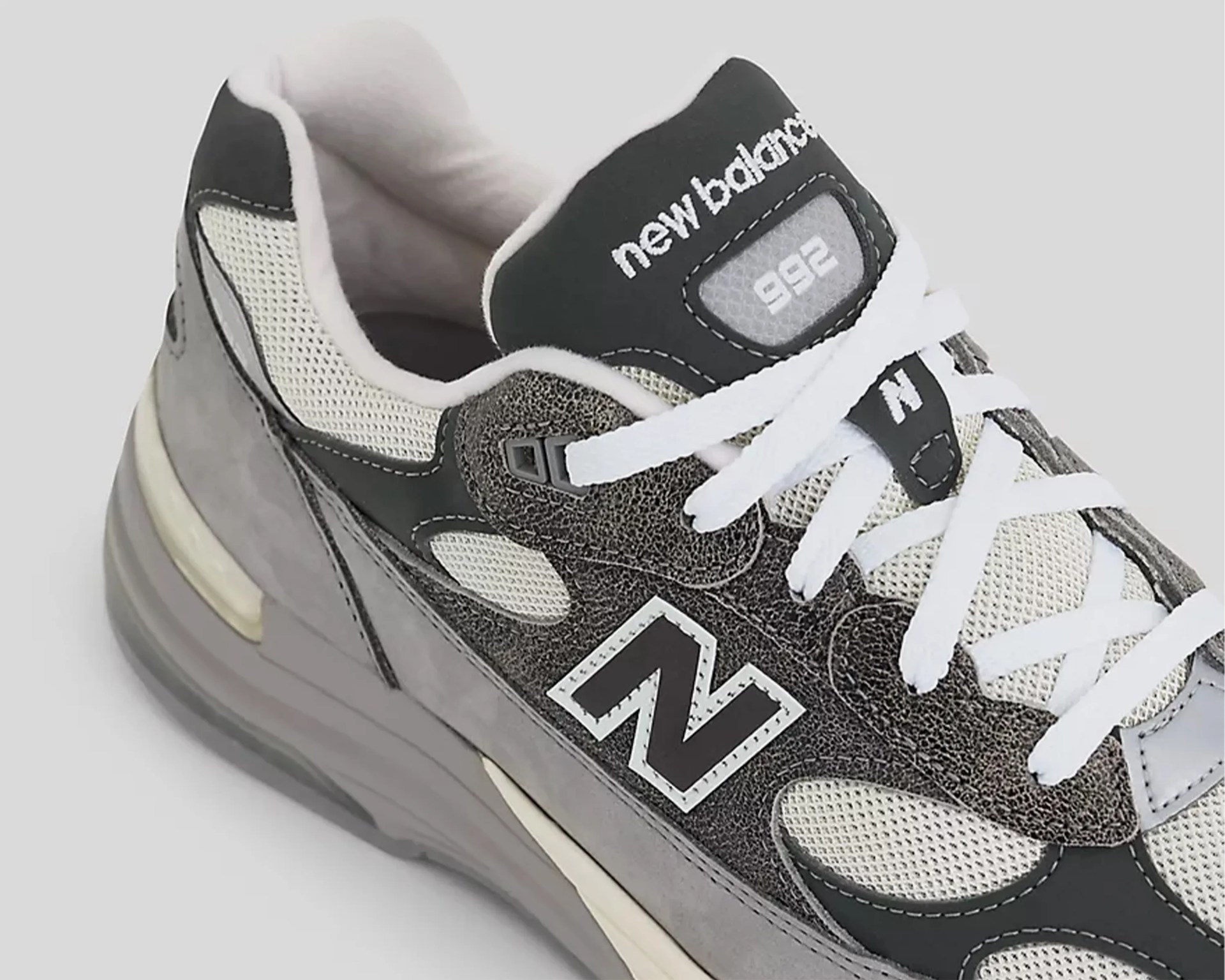Gray and black New Balance 992 sneaker with white laces and mesh panels.