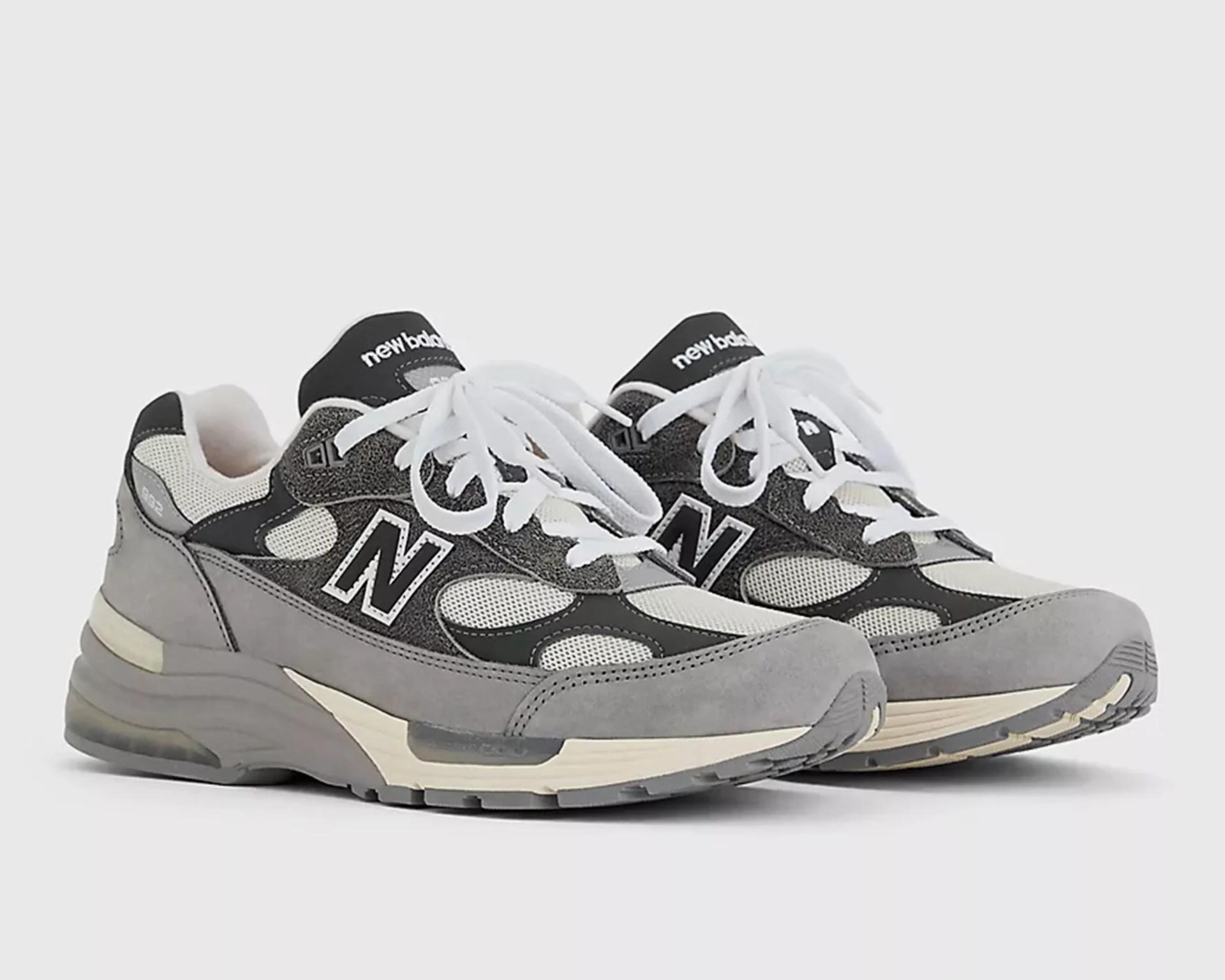 Pair of gray and black New Balance sneakers with white laces and mesh panels on a white background.