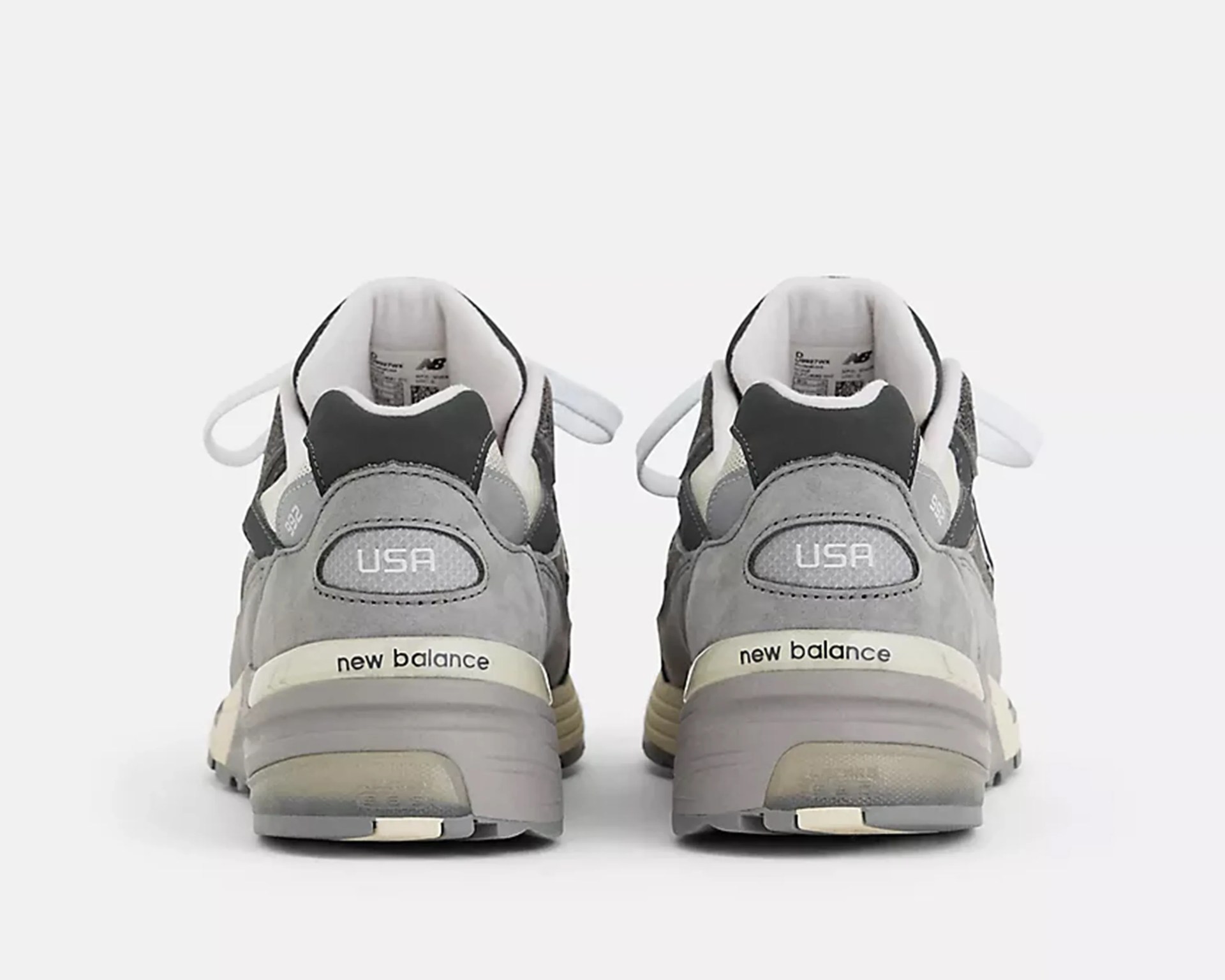 Pair of gray and white New Balance sneakers viewed from the back with "USA" and "new balance" text visible.