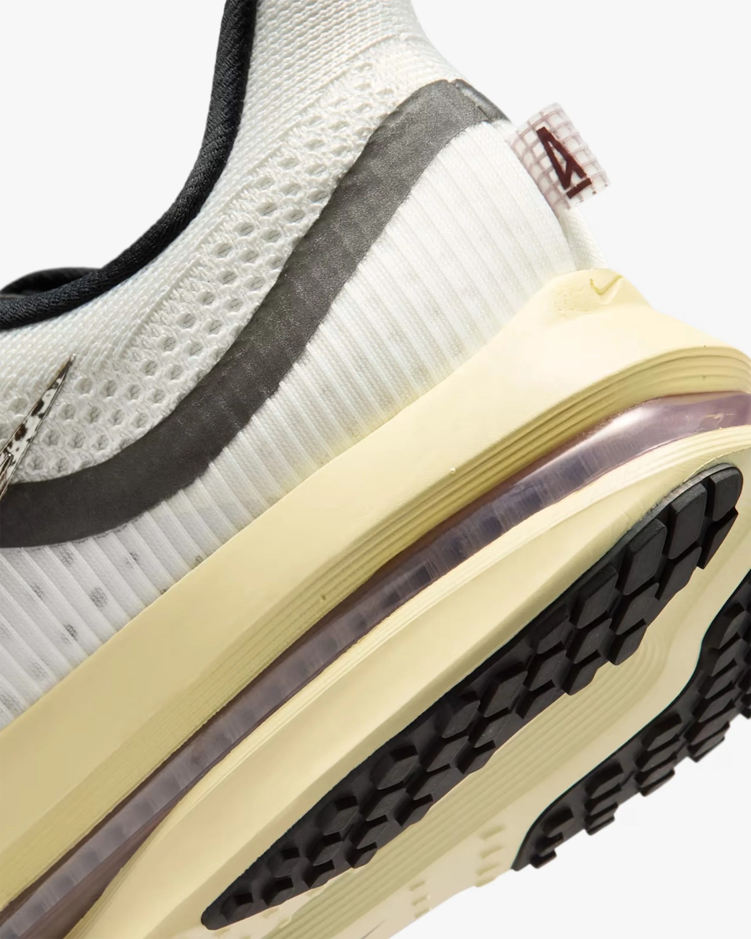 Close-up of a white and cream sneaker heel with black outsole and a small fabric pull tab featuring the number 4.