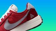 Red and gray Nike ACG sneaker with white laces and a thick white sole against a blue-green gradient background.