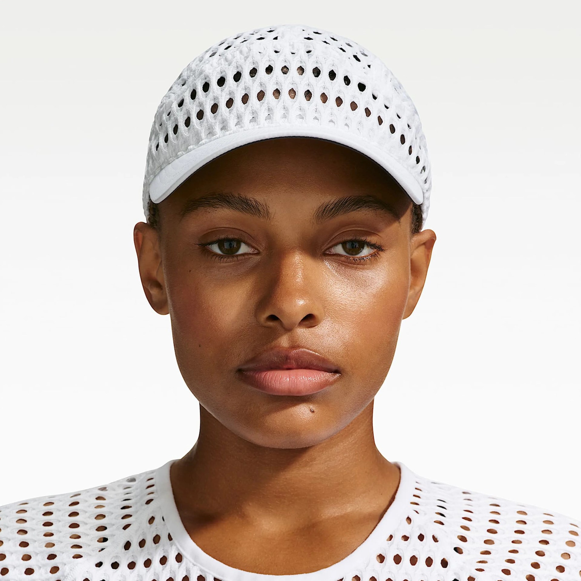 White mesh baseball cap with a curved brim worn by a person.
