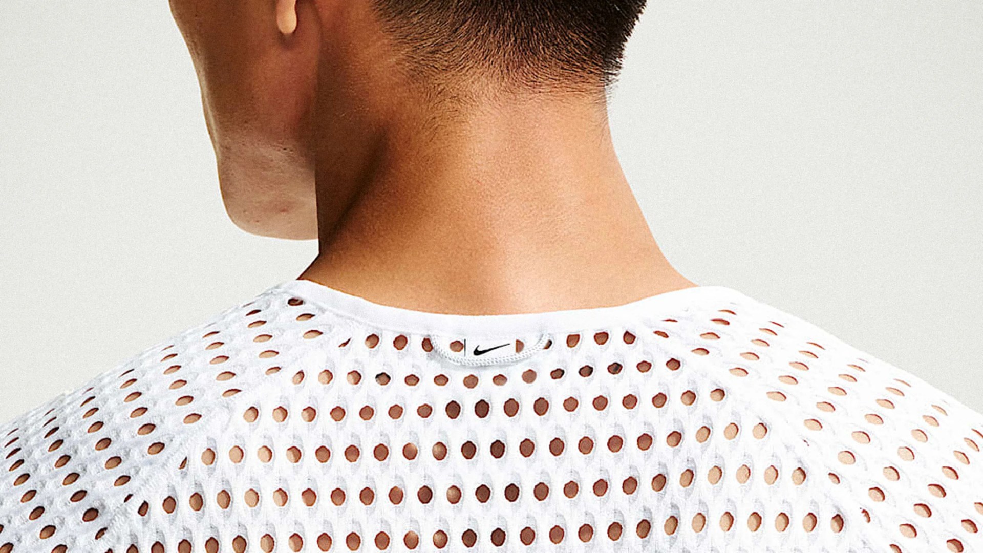 Close-up of a person's neck and upper back wearing a white perforated Nike shirt with a small black swoosh logo on the collar.