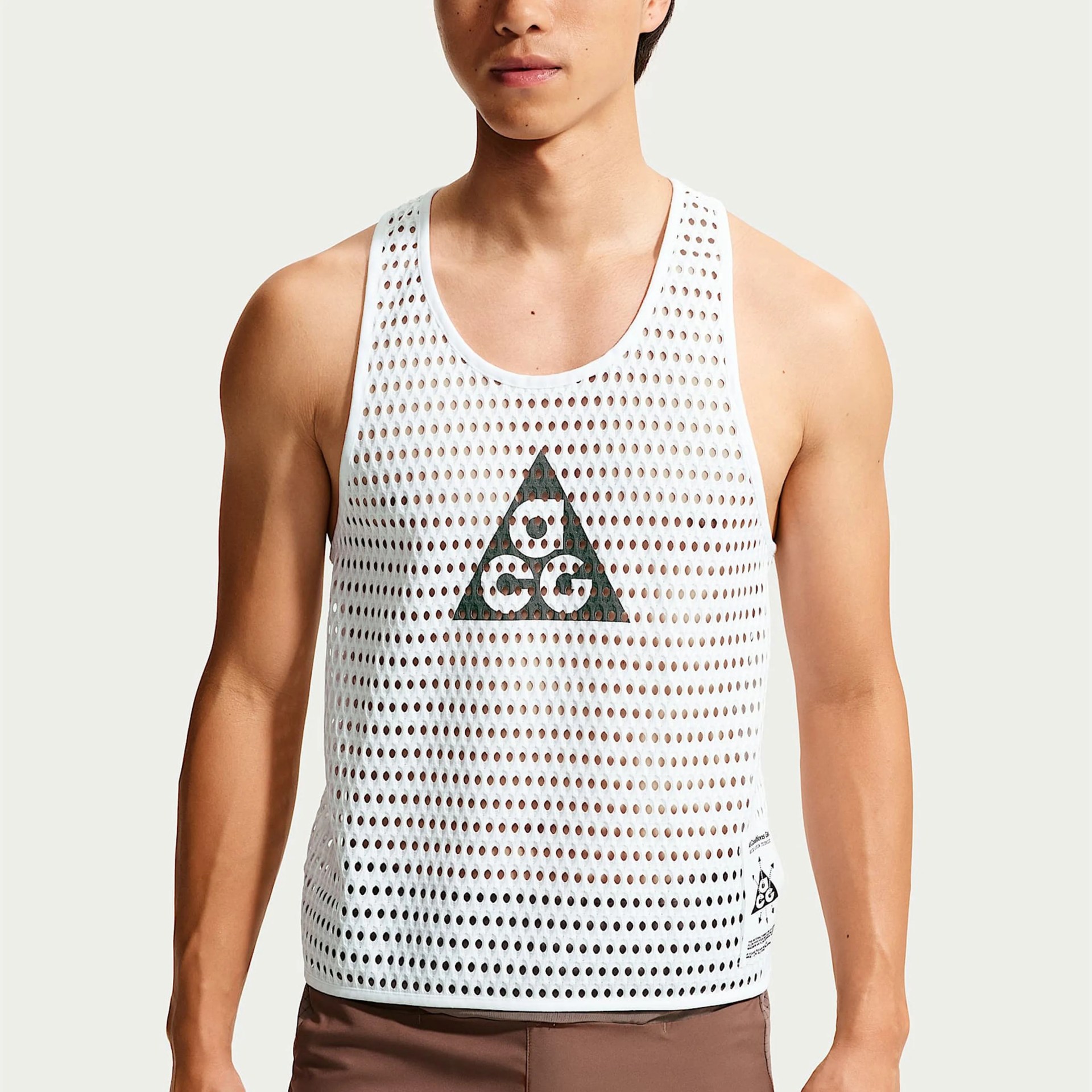 White mesh tank top with a black triangular logo worn by a person.