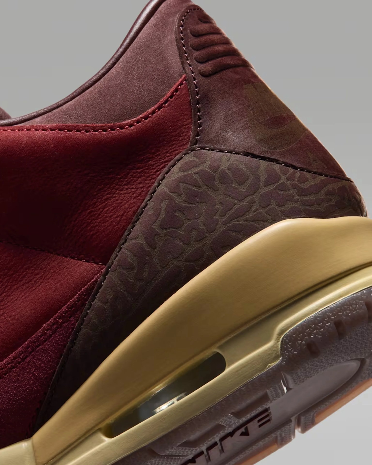 Close-up of a maroon and brown sneaker heel with textured patterns and a translucent yellow sole.