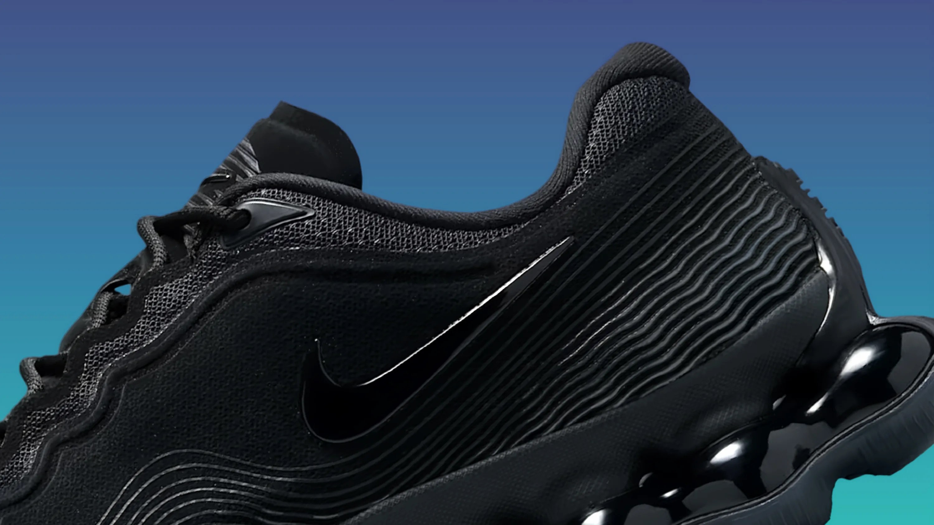 Close-up of a black Nike sneaker with textured fabric, wavy design lines, and a glossy black sole.