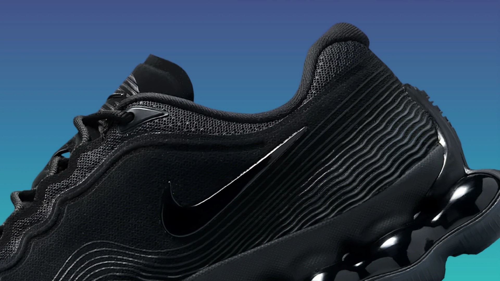 Close-up of a black Nike sneaker with textured fabric, wavy design lines, and a glossy black sole.