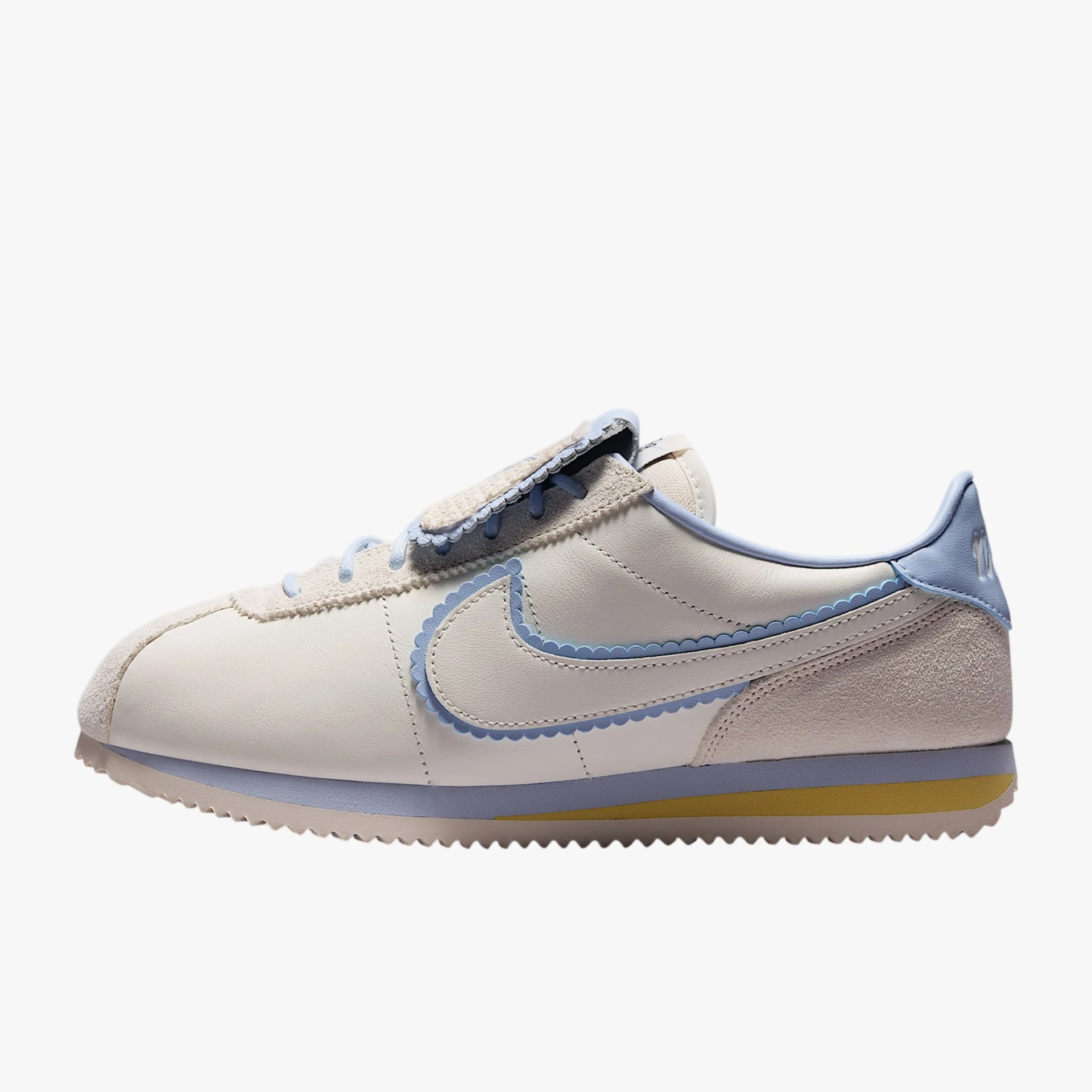 Off-white leather sneaker with light blue scalloped trim and suede accents on a white background.