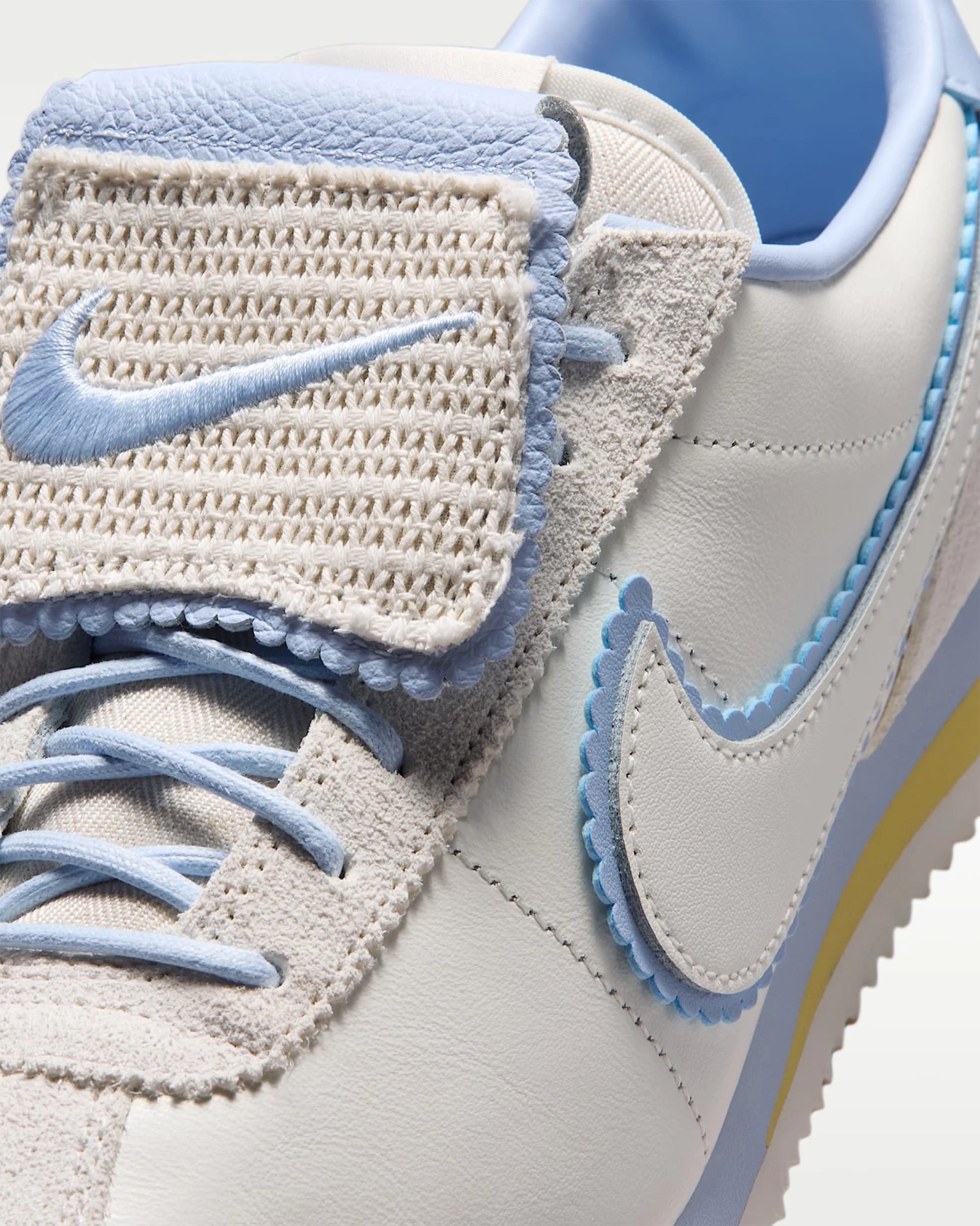 Close-up of a white and light blue Nike sneaker with textured woven tongue and scalloped edges on the swoosh and tongue.