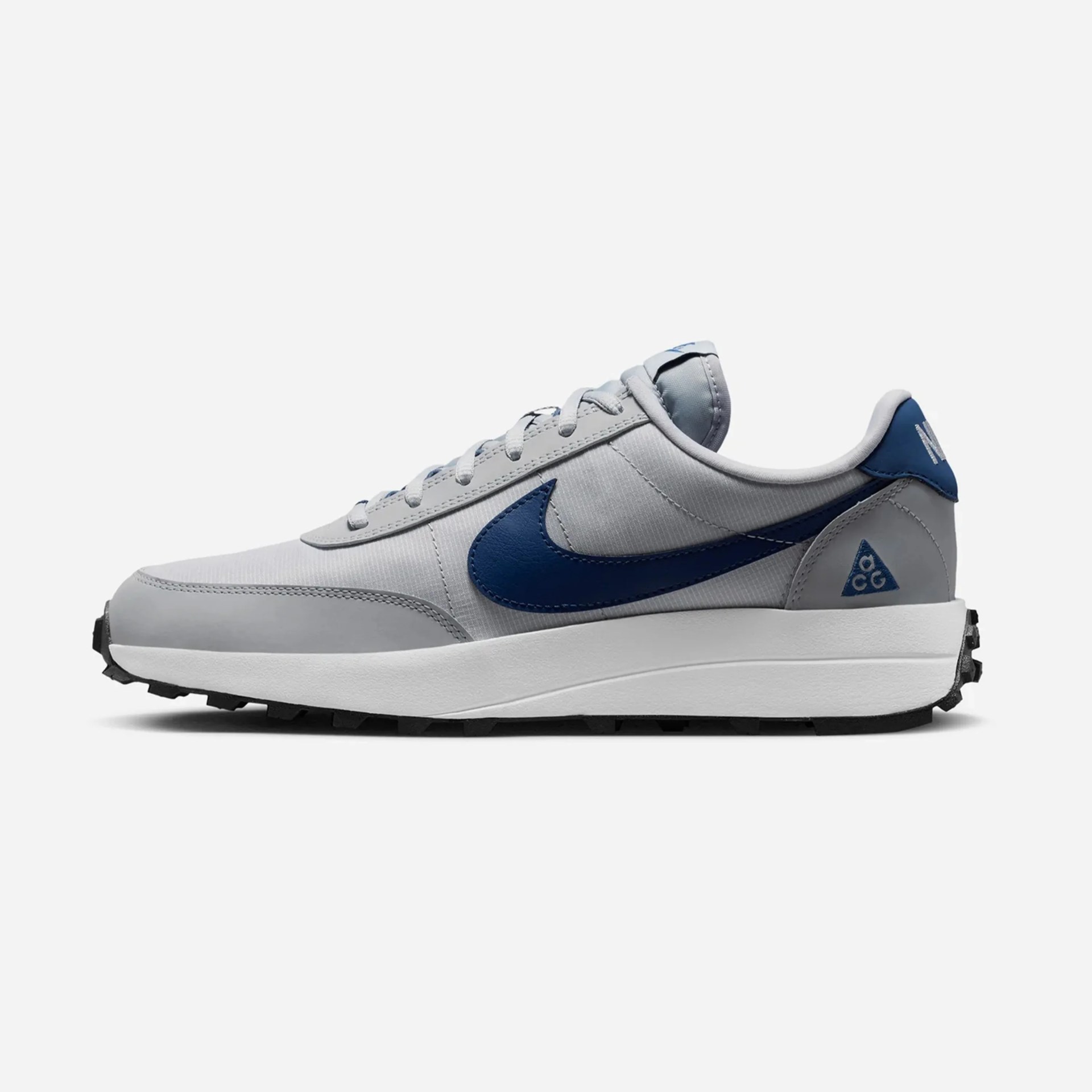 Light gray Nike sneaker with dark blue swoosh and heel tab, white midsole, and black outsole.