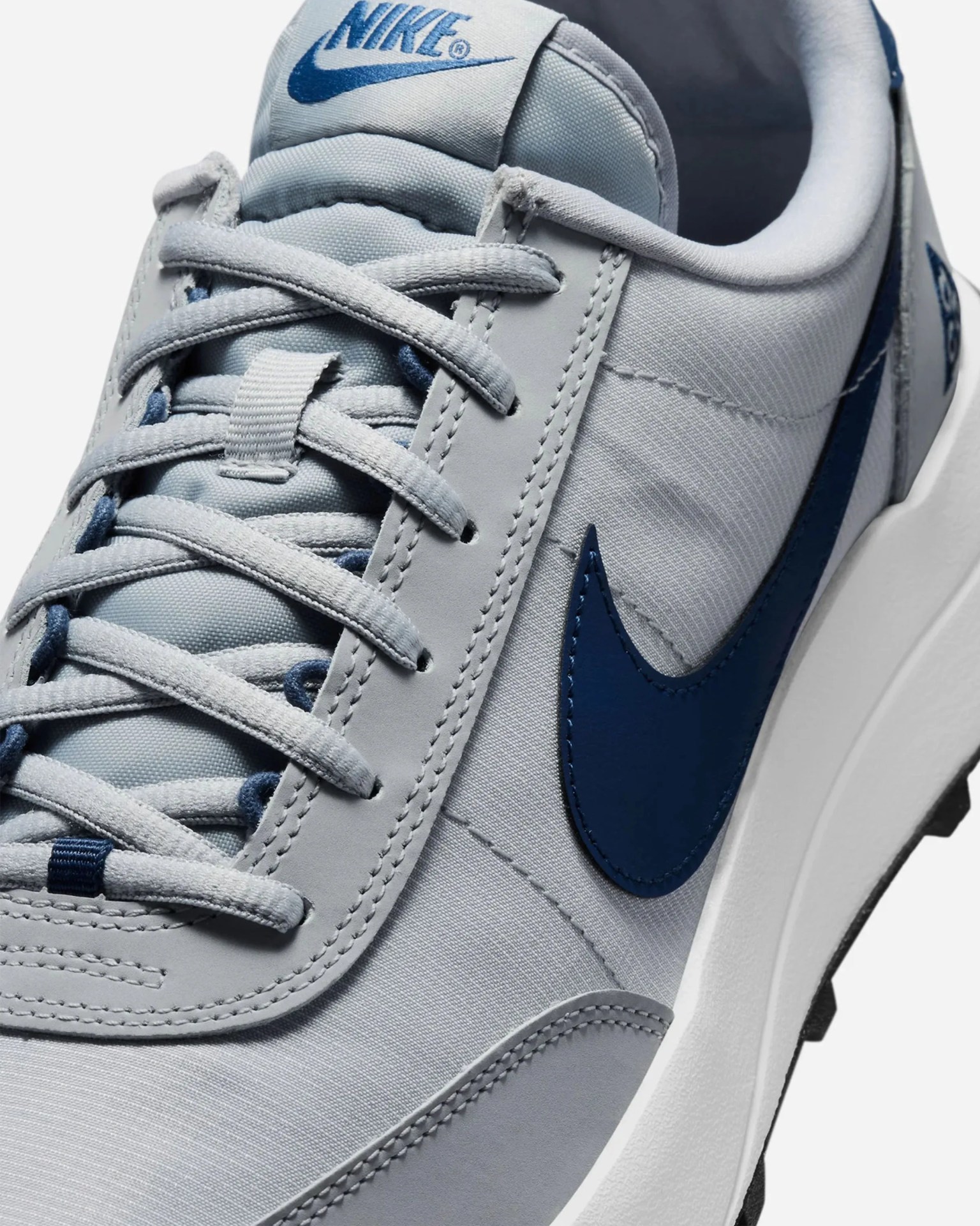Light gray Nike sneaker with blue swoosh logo and matching blue Nike branding on the tongue.
