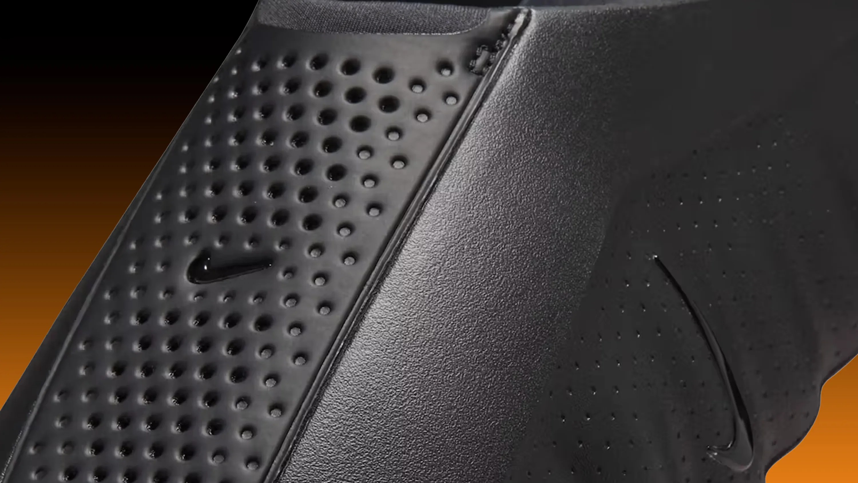 Close-up of black Nike shoe with perforated and textured panels and small Nike swoosh logos.