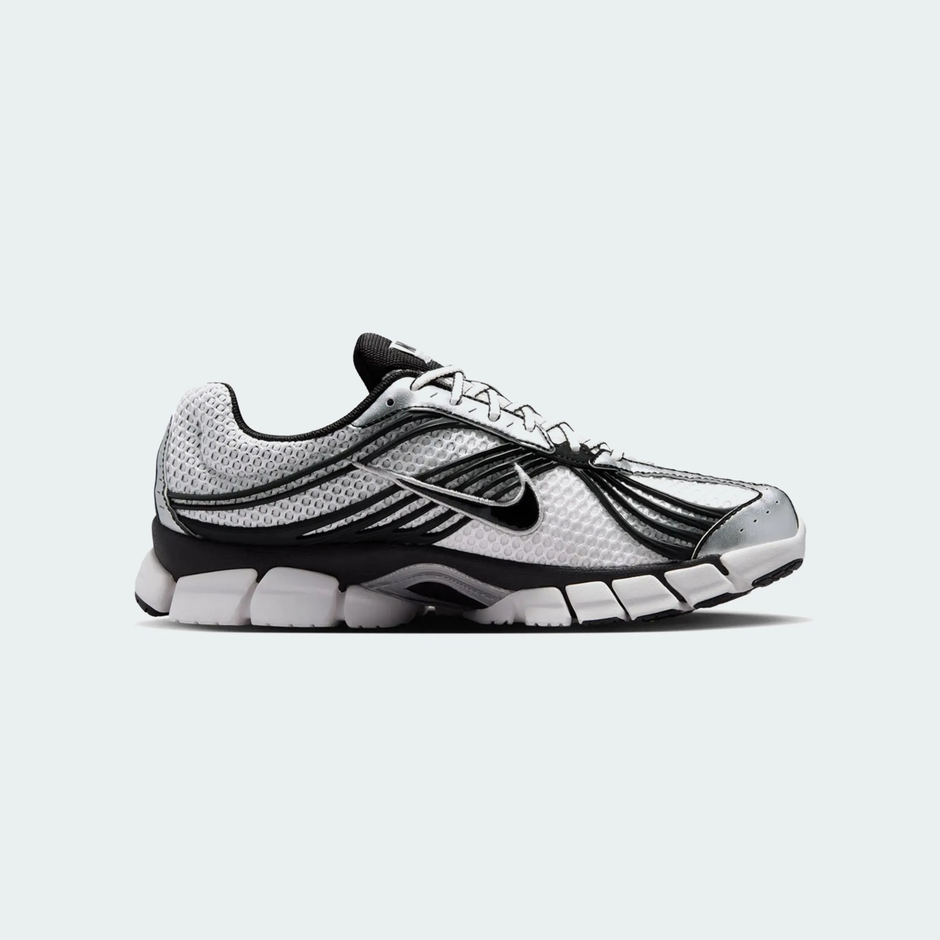 White and black Nike running shoe with mesh upper and segmented sole on a light background.
