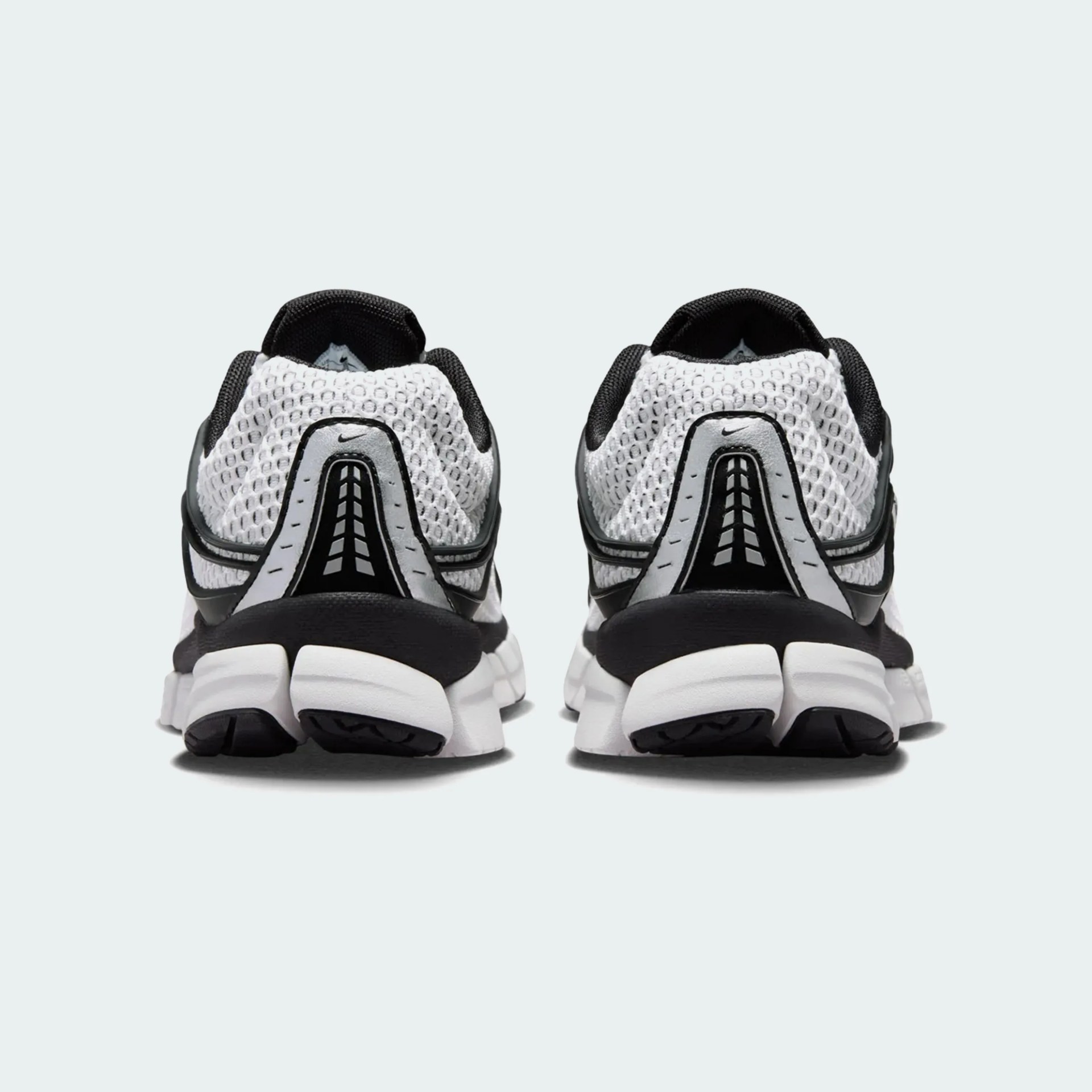 Pair of white and black Nike sneakers viewed from the back showing mesh upper and segmented sole.