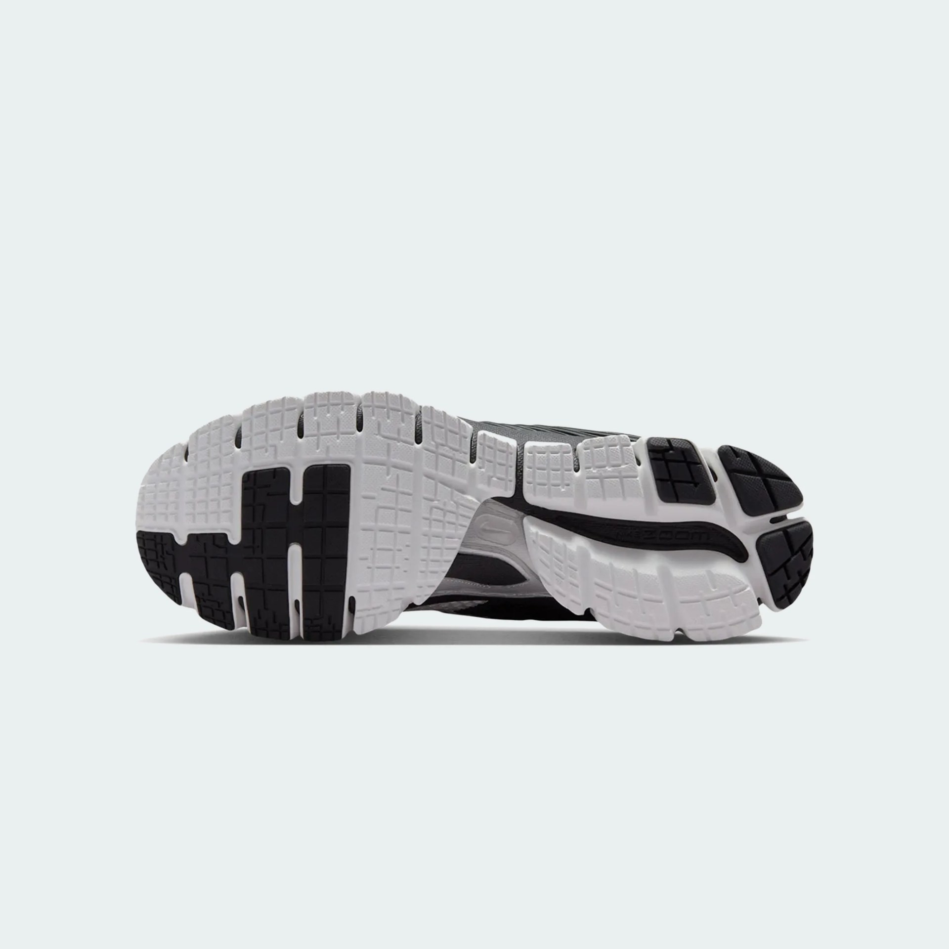Black and white rubber outsole of a running shoe with segmented tread pattern and "Zoom" branding.