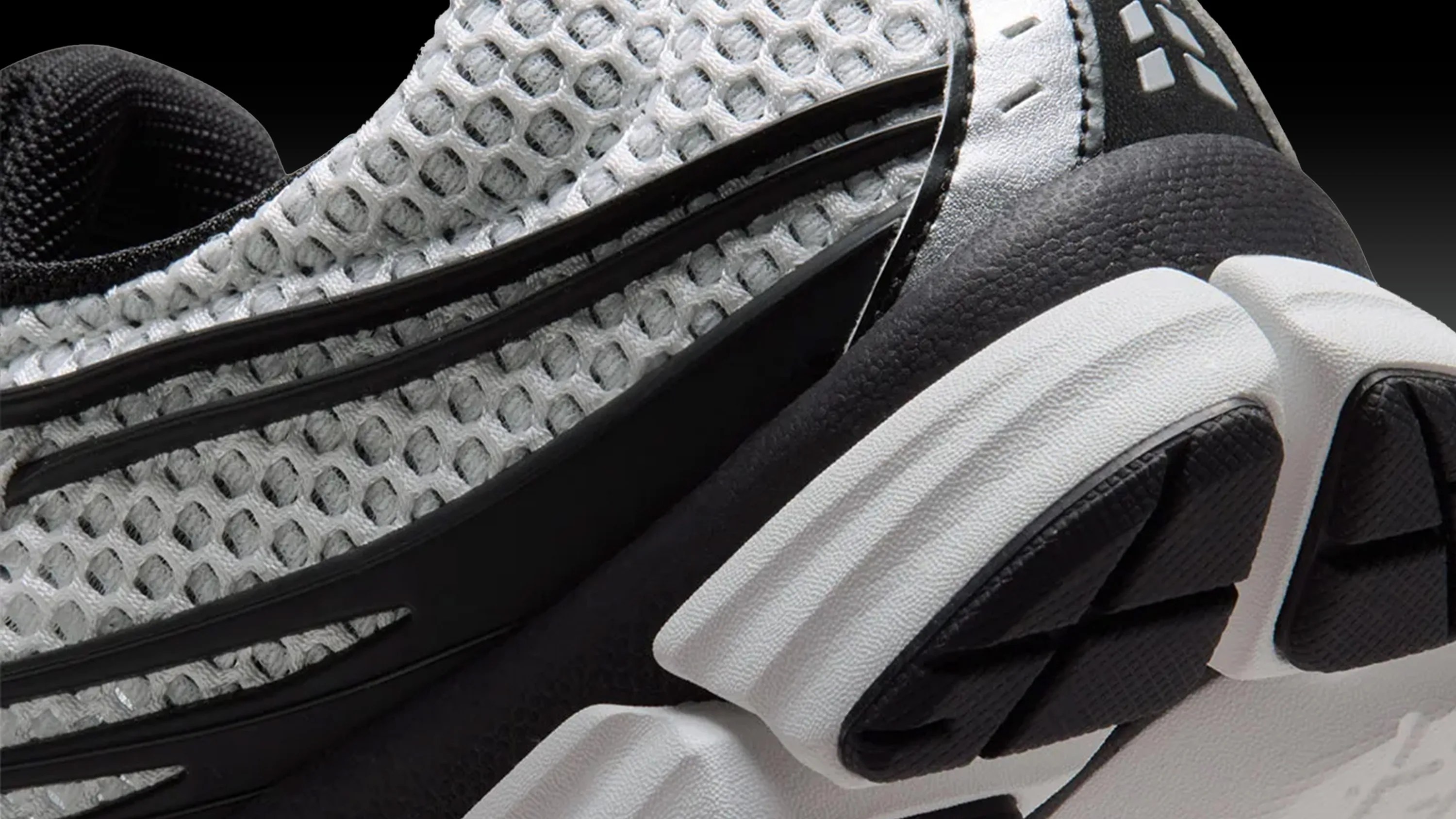 Close-up of a black and white sneaker with mesh upper and textured sole.