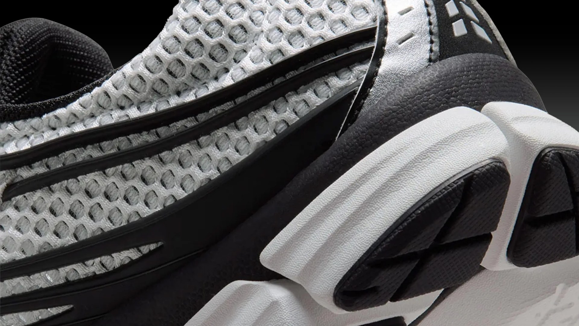 Close-up of a black and white sneaker with mesh upper and textured sole.