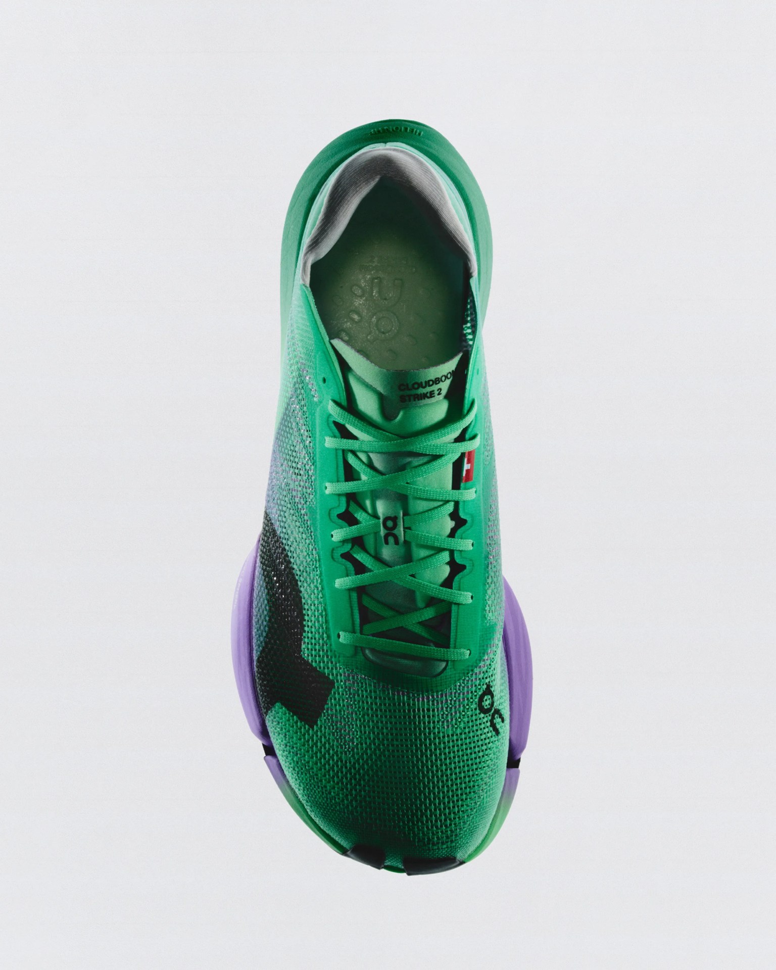 Green and purple On Cloudboom Strike 2 running shoe viewed from above on a white background.