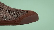Close-up of a brown woven mesh shoe toe with a rubber sole on a green background.