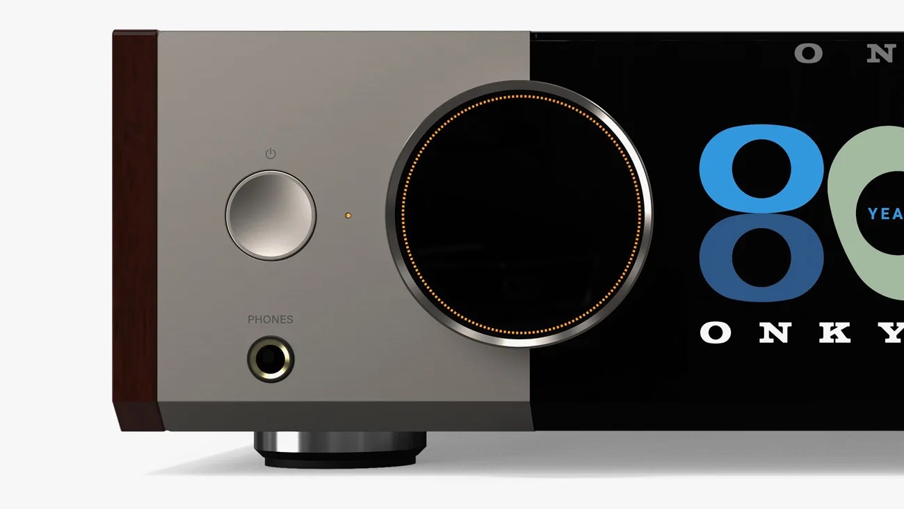 Close-up of a stereo receiver front panel with a large volume knob, power button, headphone jack, and wood side panel.