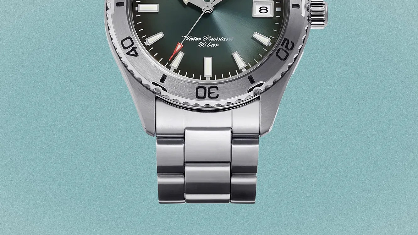 Close-up of a silver metal watch band attached to a watch with a green dial and rotating bezel.