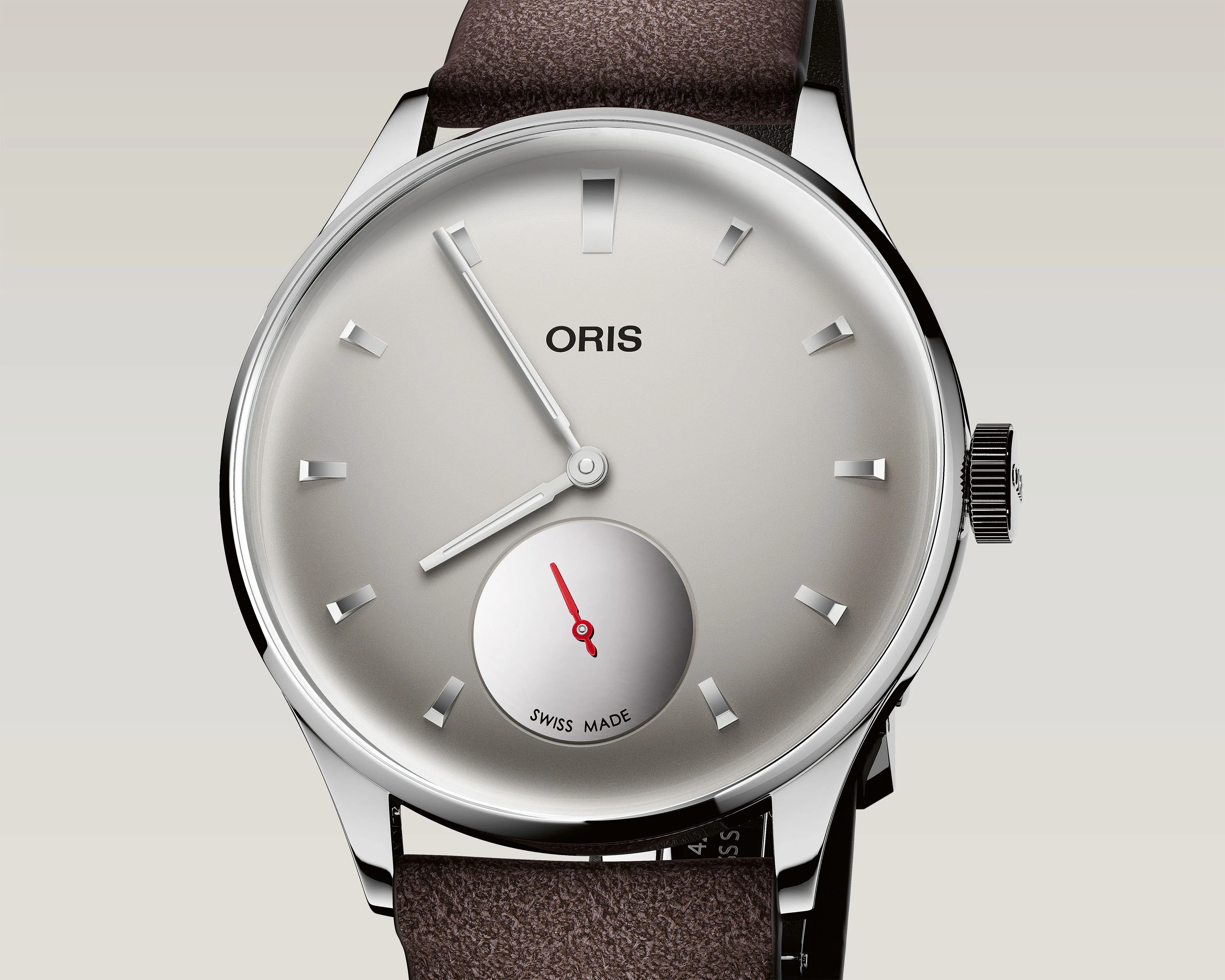 Silver Oris wristwatch with minimalist dial, silver hour markers, white hands, red second hand in subdial, and brown leather strap.