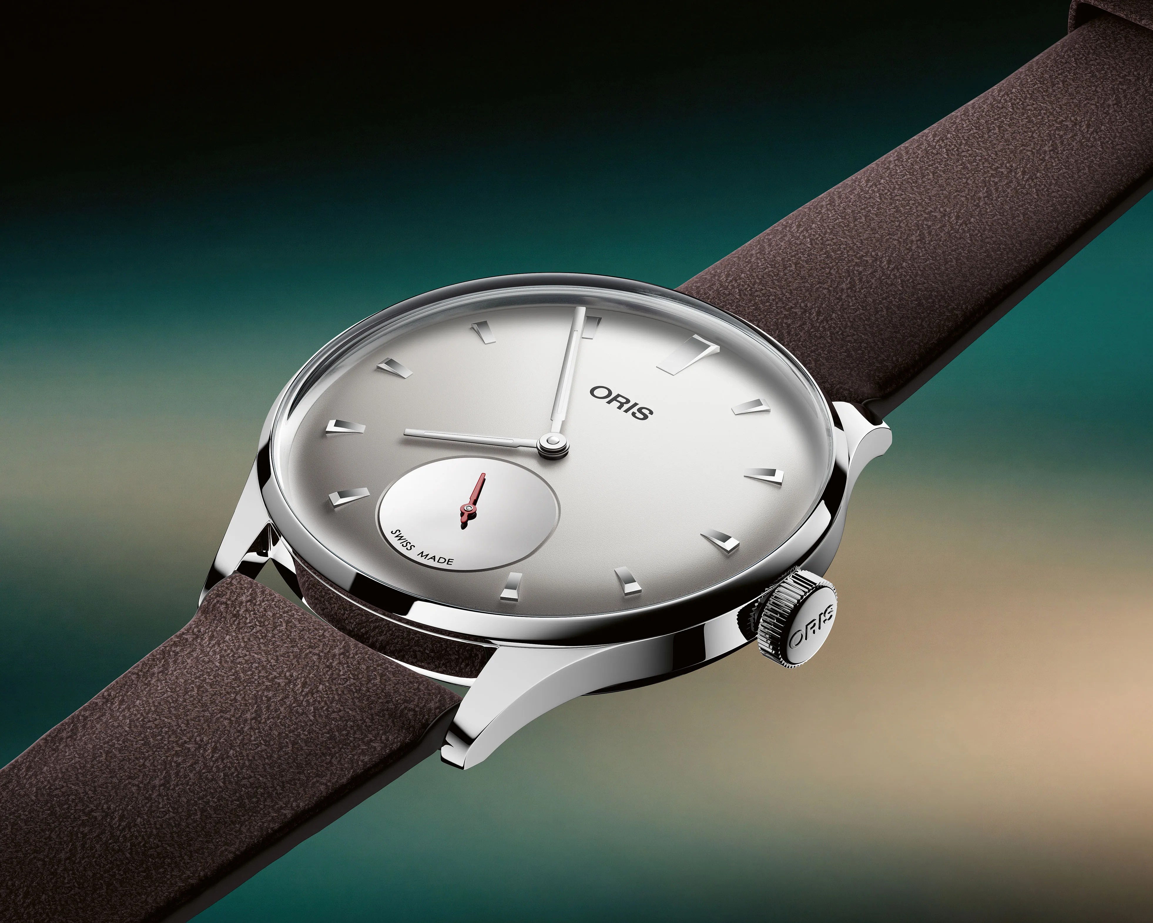 Silver Oris wristwatch with a white dial, polished case, and brown leather strap on a gradient background.