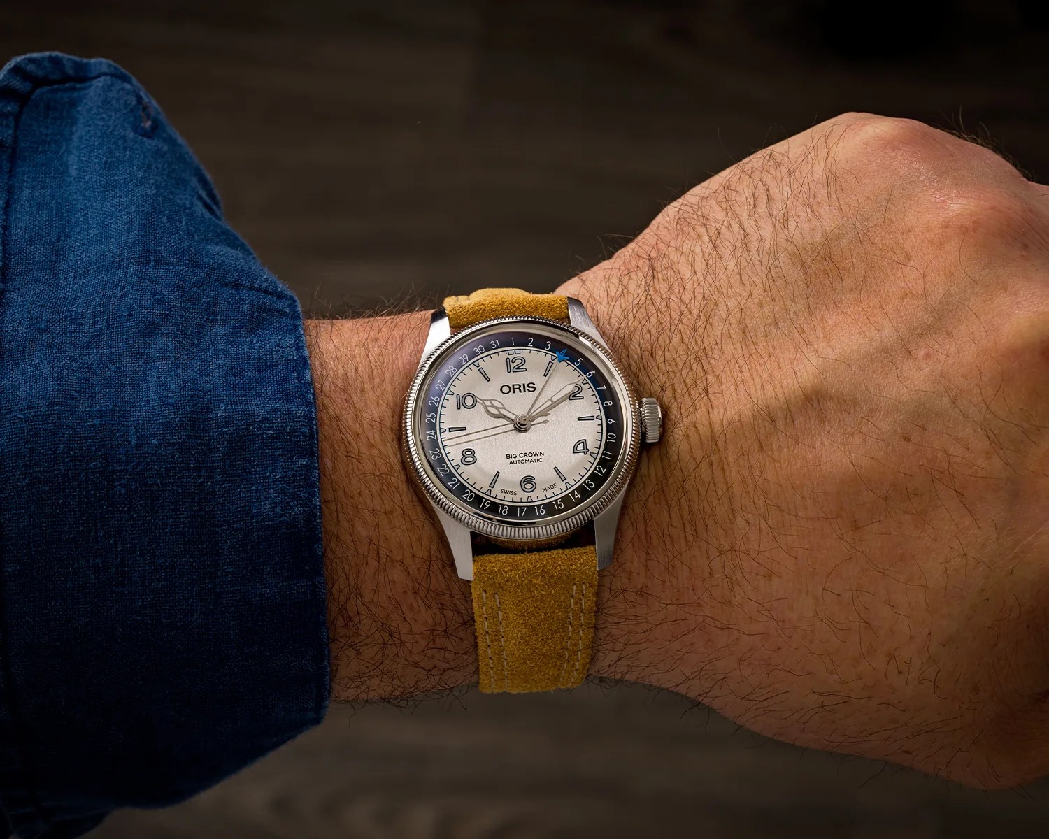 Oris Big Crown automatic wristwatch with beige dial and brown suede strap worn on a wrist.