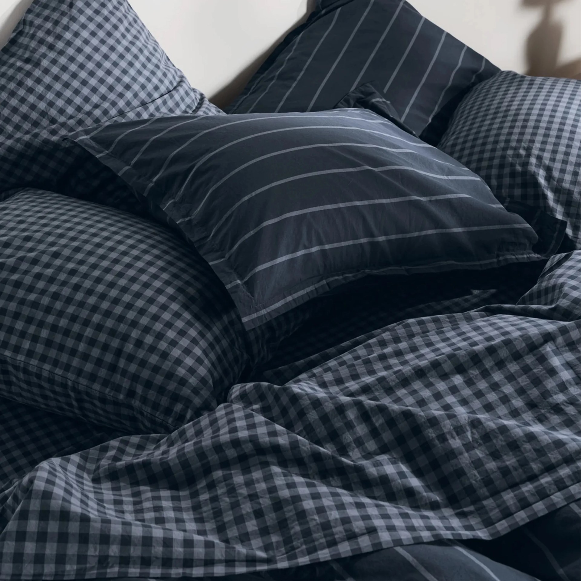 Dark blue bedding set with a mix of checkered and striped pillowcases and duvet cover.