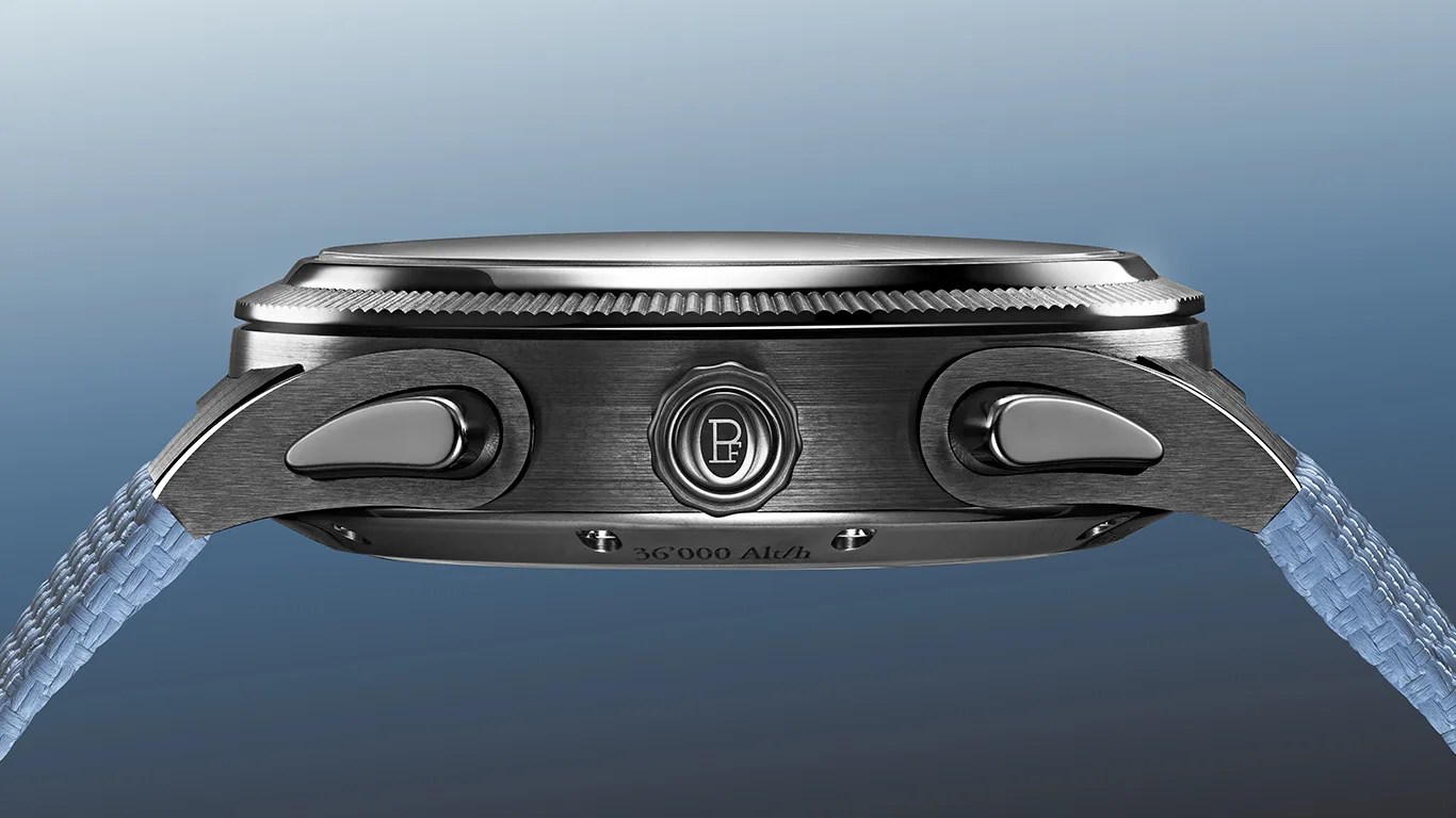 Side view of a stainless steel wristwatch case with a textured crown and two pushers, attached to a light blue woven strap.