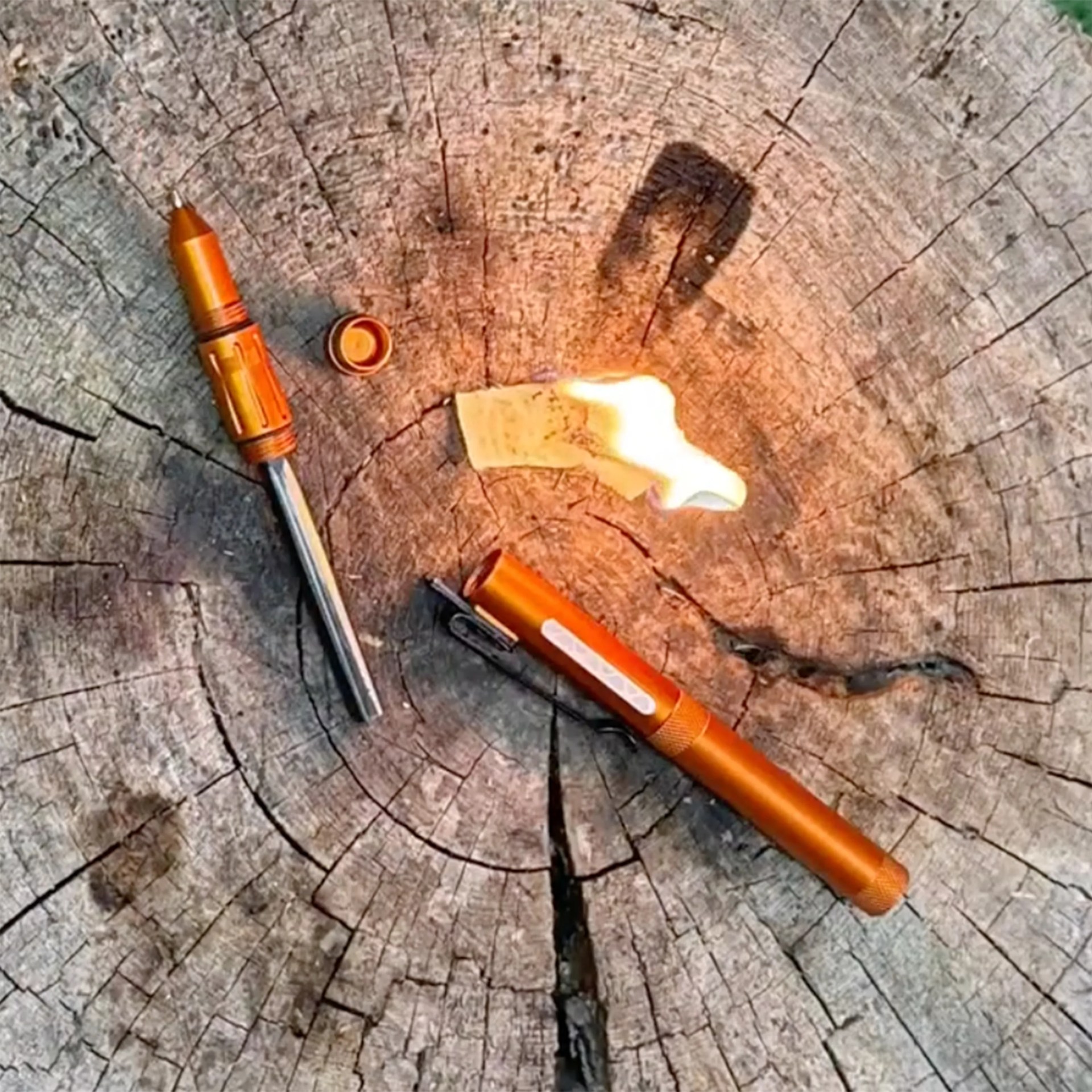 Orange fire starter with a metal rod and cap, igniting a flame on a wooden tree stump surface.