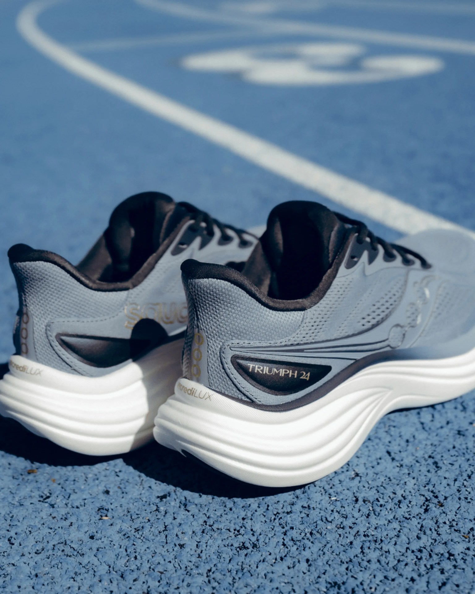 Pair of gray and black Saucony Triumph 24 running shoes on a blue textured surface.