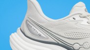 Close-up of a white Saucony Triumph 24 running shoe heel with mesh upper and cushioned sole against a blue background.