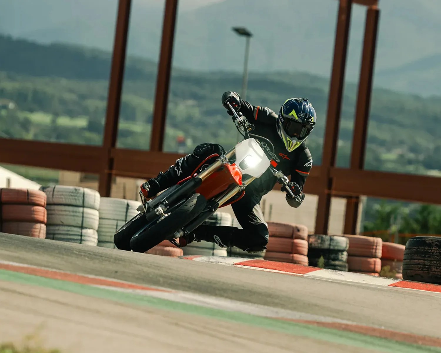Motorcyclist in black gear leaning into a turn on a red and white sport bike on a racetrack.