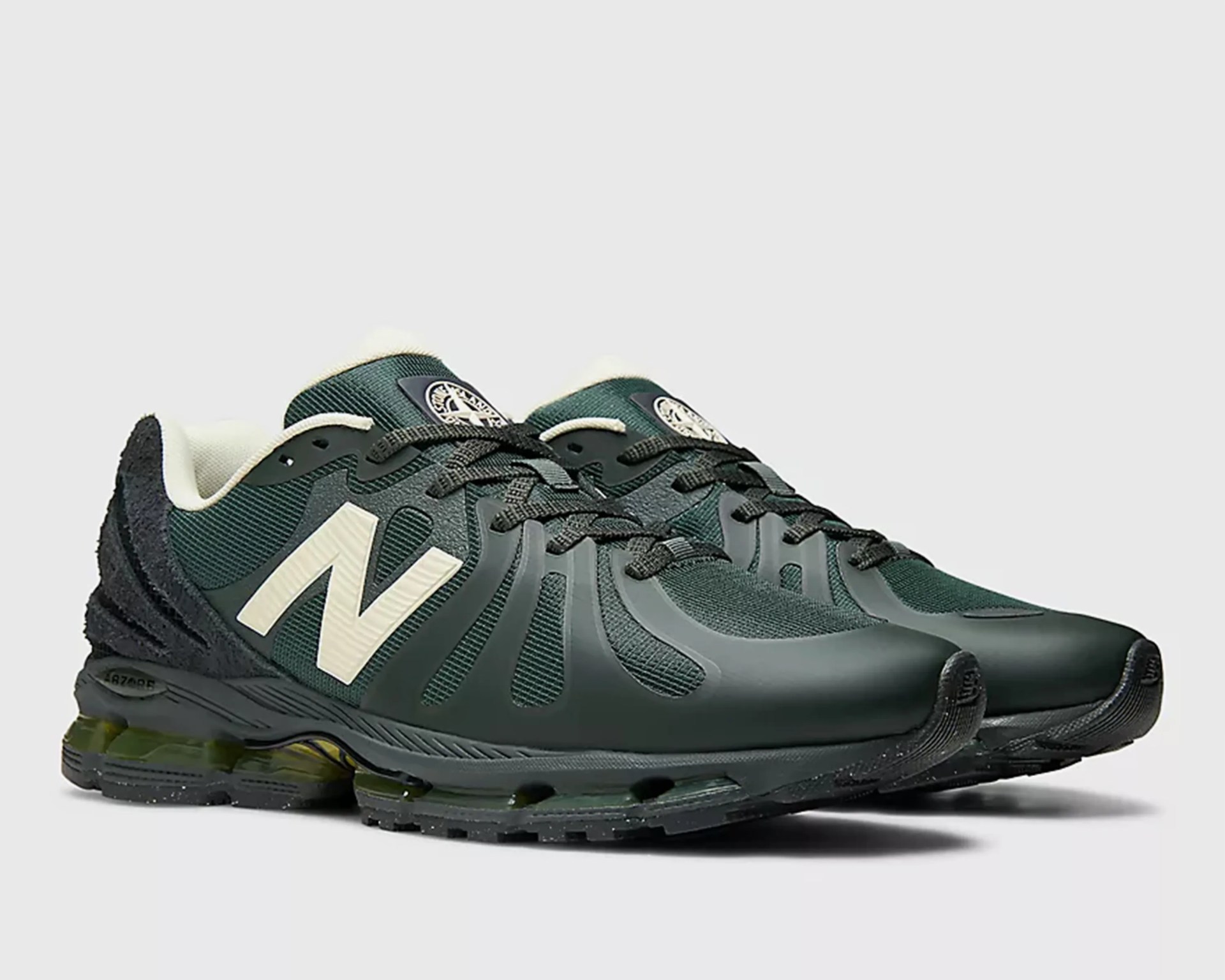 Pair of dark green New Balance sneakers with white logo and black soles on a white background.