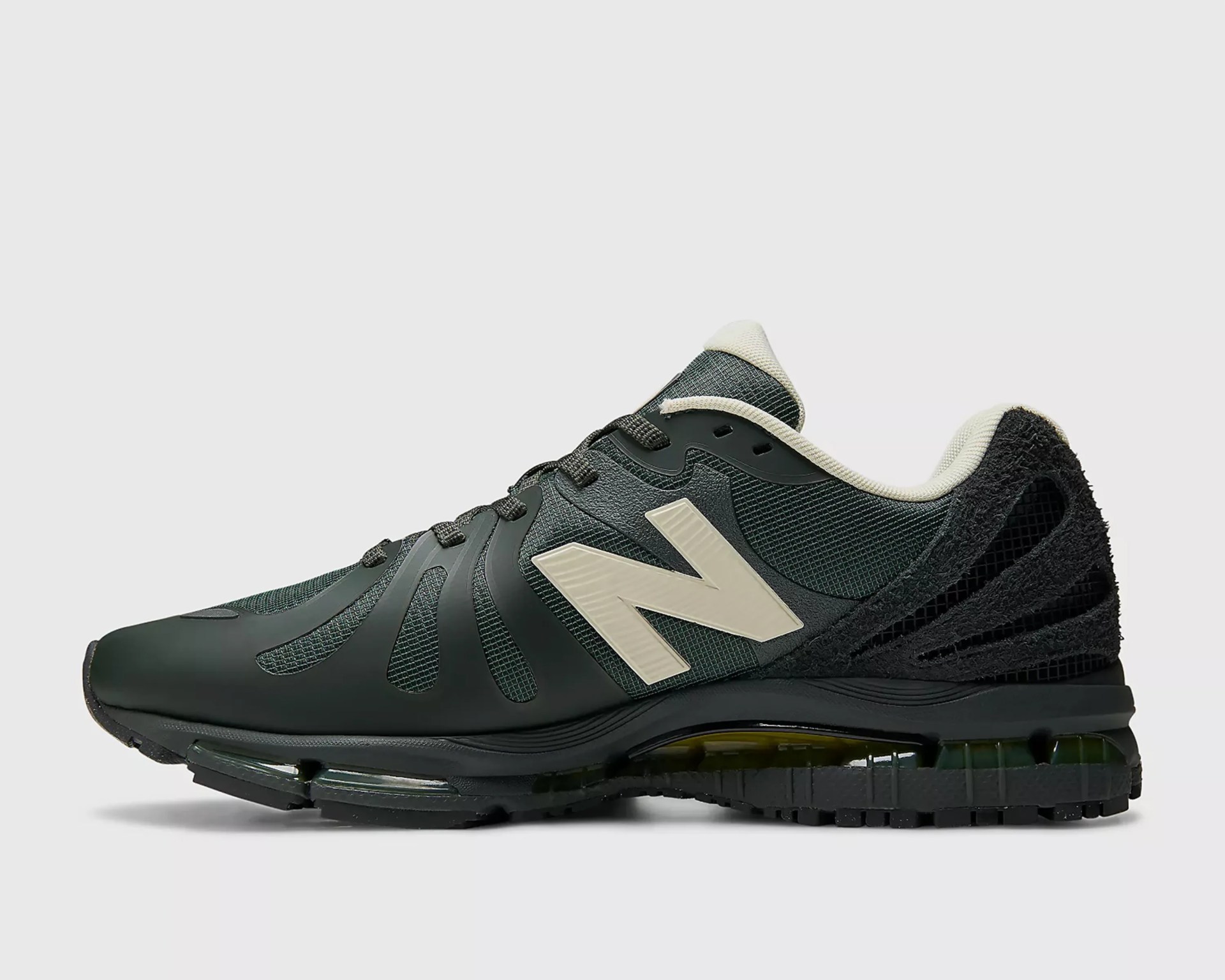 Dark green New Balance sneaker with cream logo and padded collar, featuring a textured sole and mesh upper.