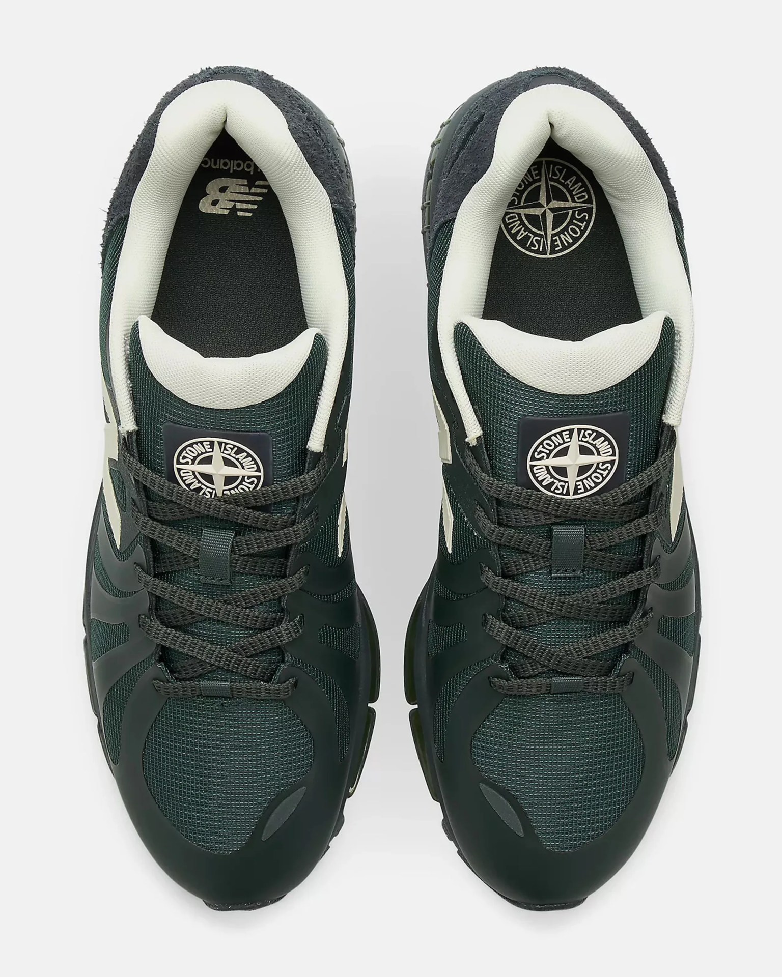 Pair of dark green and black sneakers with white padded collars and Stone Island logos on the tongues and insoles.