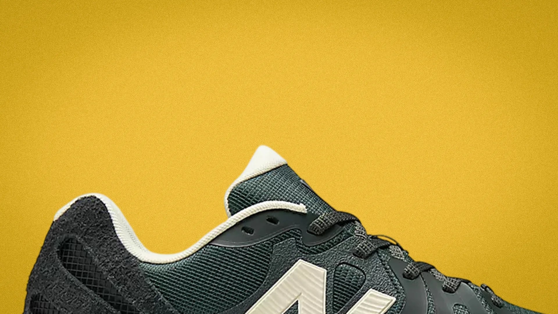 Close-up of a black and white New Balance sneaker against a yellow background.