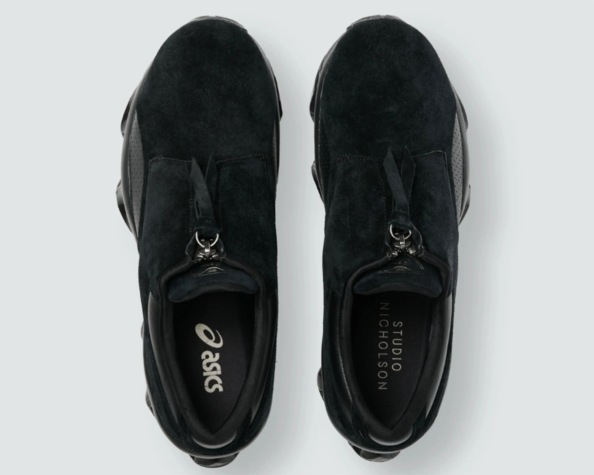 Pair of black suede sneakers with zipper closure and black rubber soles viewed from above.