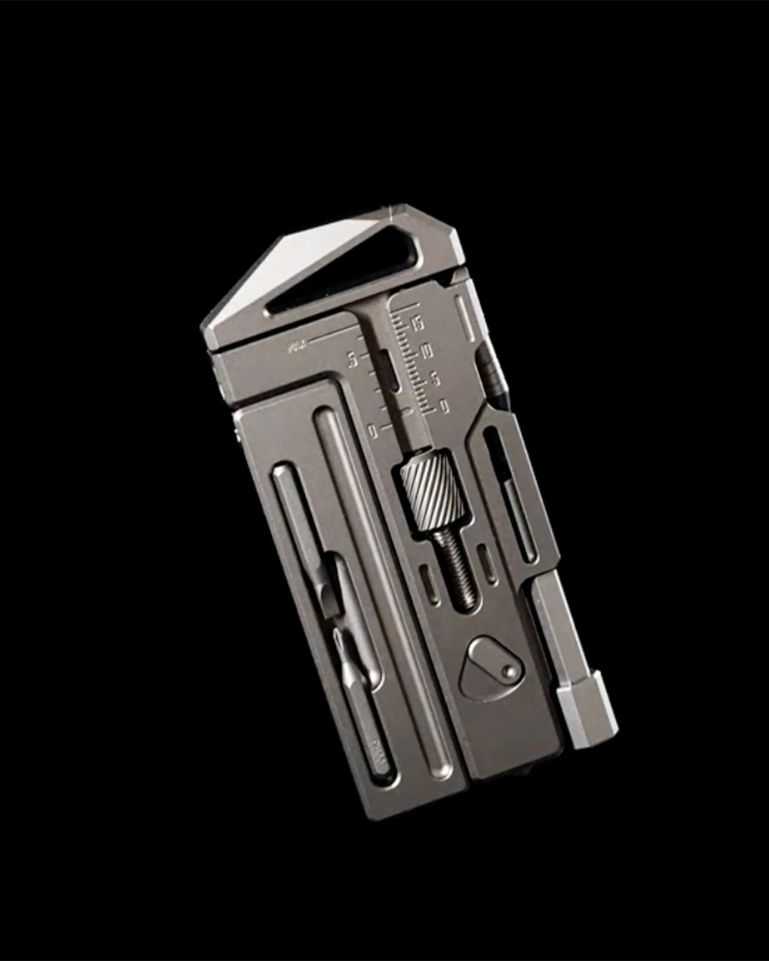 Close-up of a metallic multi-tool with a wrench, screwdriver bit, and measurement markings on a black background.