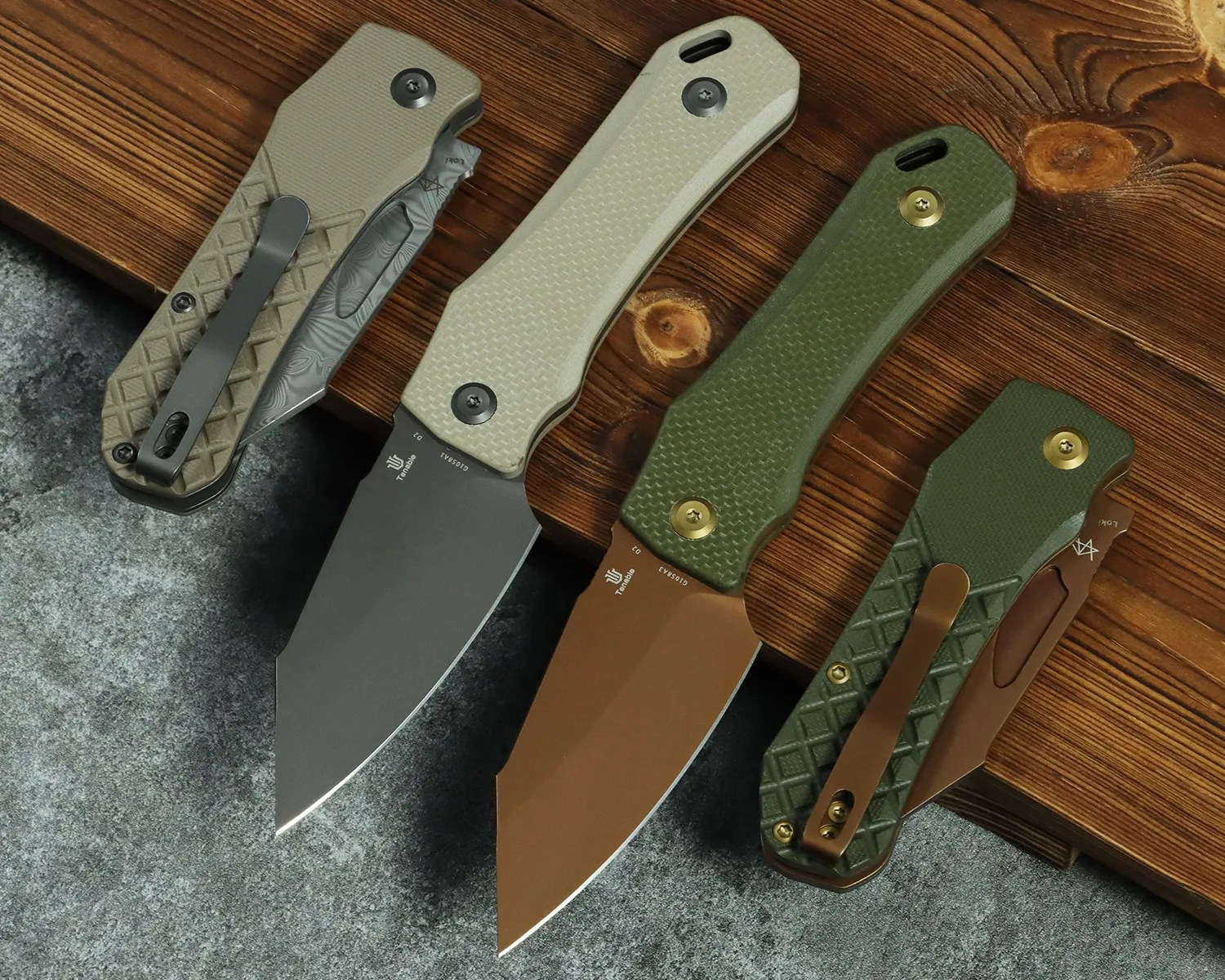 Four folding knives with textured handles in tan and green, two with blades open and two closed, displayed on a wooden surface.