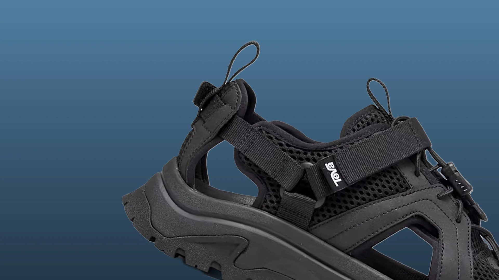 Black Teva sandal with mesh upper, adjustable straps, and rugged sole on a blue background.