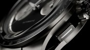 Close-up of a titanium watch bezel and side pusher with engraved tachymeter scale markings.