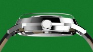 Side view of a polished silver watch case with a crown and black leather strap against a green background.